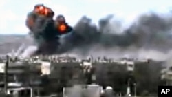 This video image taken from amateur video and broadcast by Bambuser/Homslive shows a series of devastating explosions in the central Syrian city of Homs, Syria, June 11, 2012.