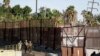 FILE - Marines patrol during work to fortify the border structure that separates Tijuana, Mexico, behind, and San Diego, near the San Ysidro Port of Entry, Nov. 9, 2018, in San Diego. 