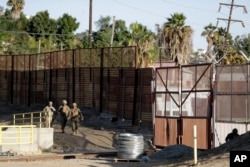 Marines patrol during work to fortify the border structure that separates Tijuana, Mexico, behind, and San Diego, near the San Ysidro Port of Entry, Nov. 9, 2018, in San Diego.