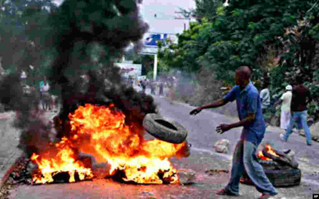 A Haitian throws a tire into fire during a protest following presidential elections in Port-au-Prince December 8, 2010. Protests and sporadic gunfire erupted in Haiti's capital late on Tuesday after electoral authorities announced the country's inconclusi