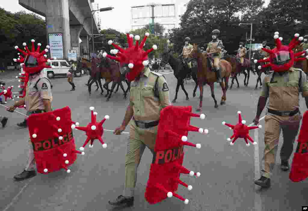 Indian police officers walk wearing virus themed helmet durig an awareness drive aimed at preventing the spread of the coronavirus in Hyderabad.