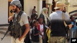 Children and families are seen stranded outside a mosque guarded by revolutionary fighters in Sirte, Libya. After NATO's heavy bombing on Sunday, hundreds of families are leaving the city. Some remain stranded on the outskirts due to lack of transportatio