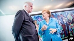 German Chancellor Angela Merkel, right, talks to Interior Minister Horst Seehofer, left, prior to the weekly cabinet meeting at the chancellery in Berlin, June 13, 2018.