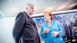 FILE - German Chancellor Angela Merkel, right, talks to Interior Minister Horst Seehofer, left, prior to the weekly cabinet meeting at the chancellery in Berlin, June 13, 2018.