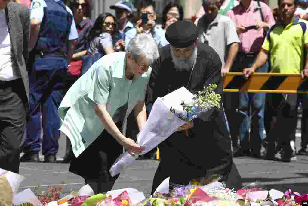 People lay flowers to pay respect to the shooting victims at a makeshift memorial at Martin Place in Sydney's Martin Place, Sydney Australia. Tuesday Dec. 16, 2014.