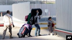 A family leaves to apply for asylum in the United States, at the border, Jan. 25, 2019, in Tijuana, Mexico. 