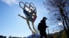 Seorang pengunjung Taman Shougang, Beijing, berjalan melewati patung yang menggambarkan perhelatan Olimpiade Musim Dingin Beijing 2022, pada 9 November 2021. AS telah mengumumkan boikot diplomatik terhadap perhelatan tersebut. (Foto: AP/Ng Han Guan)