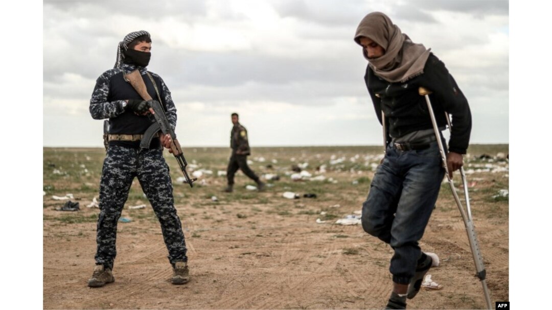 Muškarac, za kojeg se sumnja da je borac Islamske države, prolazi pored člana Sirijske demokratske snage (SDF) i ide na pretres prije nego napusti posljednji uporište Islamske države, Baghouz, Sirija, 27. februar 2019.