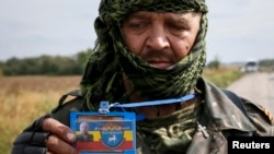 FILE - A pro-Russian separatist shows his ID card to Ukrainian journalists at a checkpoint near the town of Slavyanoserbsk, Luhansk region, eastern Ukraine, Sept. 10, 2014. Some in Ukraine see journalists operating in rebel-held areas as enemy collaborators.