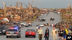 Residents of Joplin, Mo, walk west on 26th Street near Maiden Lane after a tornado hit the southwest Missouri city on Sunday evening, May 22, 2011. The tornado tore a path a mile wide and four miles long destroying homes and businesses. (AP Photo/Mike Gul