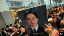 A Thai Democrat party supporter holds a poster of Thai Prime Minister and leader of the party, Abhisit Vejjajiva, during a campaign rally in Bangkok, June 23, 2011