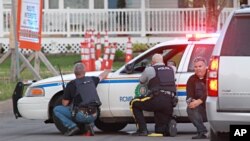 Police officers take cover behind their vehicles in Moncton, New Brunswick, June 4, 2014. 
