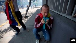 Un manifestante se arrodilla en el suelo abrumado por gases lacrimógenos despedidos por la Policía Nacional Bolivariana en Caracas, Venezuela, el sábado 8 de abril de 2017.