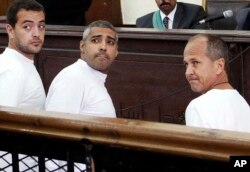 FILE - Al-Jazeera English producer Baher Mohamed, left, Canadian-Egyptian acting Cairo bureau chief Mohammed Fahmy, center, and correspondent Peter Greste, right, appear in court during their trial on terror charges, in Cairo, Egypt.