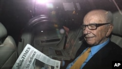 News Corp Chief Executive and Chairman Rupert Murdoch holds a copy of The Times newspaper as he leaves his home in London July 20, 2011