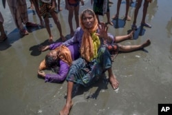 A Rohingya Muslim woman, who crossed over from Myanmar into Bangladesh, shouts for help as a relative lies unconscious after the boat they were traveling in capsized minutes before reaching shore at Shah Porir Dwip, Bangladesh, Thursday, Sept. 14, 2017. Nearly three weeks into a mass exodus of Rohingya fleeing violence in Myanmar, thousands were still flooding across the border Thursday in search of help and safety in teeming refugee settlements in Bangladesh.