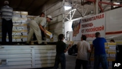 FILE - People unload a truck from a Russian humanitarian aid convoy parked at a warehouse in Makiivka, Ukraine, Sept. 17, 2015.