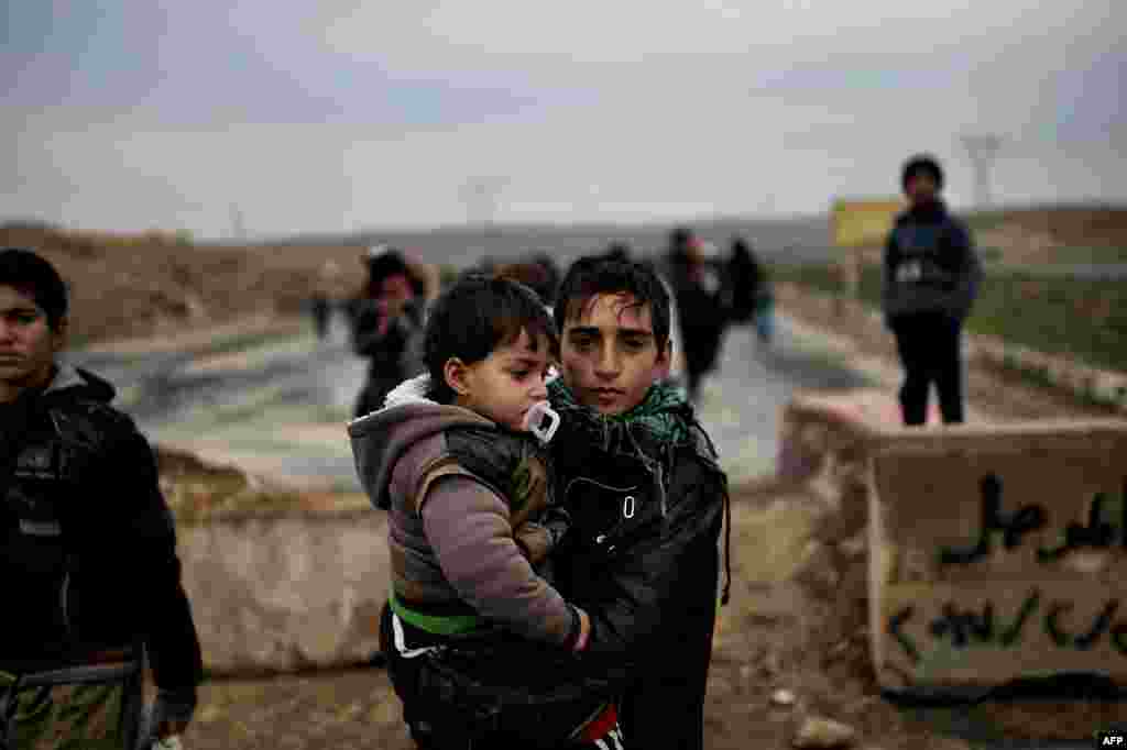 Iraqi families walk down a road as they flee Mosul, during an offensive by security forces to retake the western parts of the city from Islamic State (IS) group fighters.