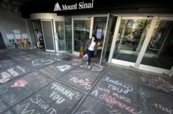 Seorang perempuan keluar dari Rumah Sakit Mount Sinai di Manhattan, melewati berbagai ucapan terima kasih di tengah pandemi Covid-19 di Kota New York, 7 April 2020. (Foto: Reuters)