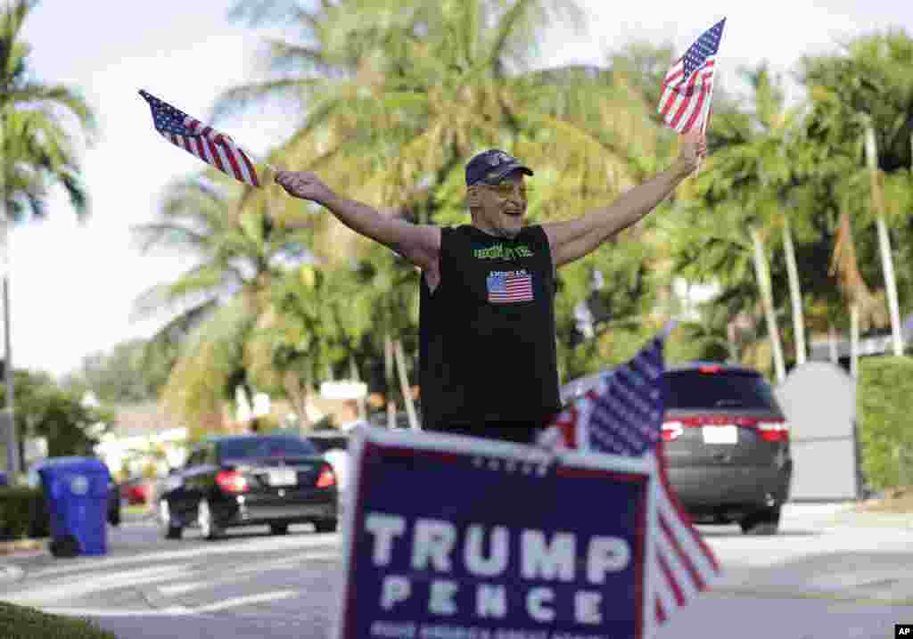 Peter Knapp, pendukung Donald Trump, melambaikan bendera Amerika di luar rumahnya di Miami (8/11). (AP/Lynne Sladky)