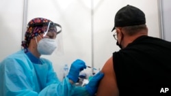 A medical worker administers a shot of Pfizer COVID-19 vaccine to Vitaly Pavlov from Rostov-on-Don at the Belgrade Fair makeshift vaccination center in Belgrade, Serbia, Oct. 2, 2021.