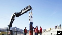 People look at a capsule that will be used to rescue trapped miners from the collapsed San Jose mine in Copiapo, Chile, 25 Sept. 2010