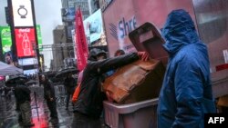 Seorang pria sedang membuang sampah di Times Square, New York, 28 Desember 2018. (Foto: AFP)