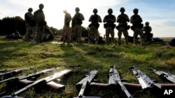 FILE - Weapons lie on the ground as Ukrainian personnel take a break during training at a military base with UK Armed Forces in Southern England on Oct. 12, 2022. 