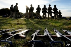 Sejumlah senjata tergeletak di tanah saat personel Ukraina beristirahat selama pelatihan di pangkalan militer dengan Angkatan Bersenjata Inggris di Inggris Selatan pada 12 Oktober 2022. (Foto: AP)