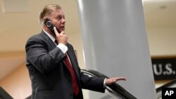 Sen. Lindsey Graham, R-S.C., talks on the phone as he rides the escalator on Capitol Hill in Washington, July 10, 2019, as he heads to a briefing on election security. 