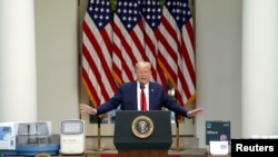 U.S. President Donald Trump gestures toward coronavirus disease testing machines as he holds an outbreak response news briefing in the Rose Garden of the White House in Washington, May 11, 2020. Vice President Mike Pence was notably absent.