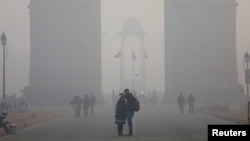 FILE - People take a selfie in front of the India Gate war memorial on a smoggy winter morning in New Delhi, India, Dec. 26, 2017.