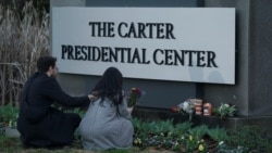 Žena drži cvijeće ispred natpisa za The Carter Presidential Center nakon smrti bivšeg predsjednika SAD Jimmyja Cartera u dobi od 100 godina u Atlanti, Georgia, 29. decembra 2024.