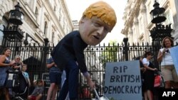 Sorang demonstran mengenakan topeng PM Boris Johnson dalam aksi demo di luar Downing Street di London, mengecam kebijakan Johnson, Rabu (28/8).