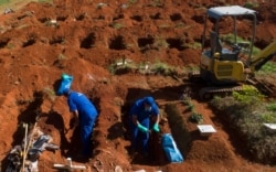 Cemetery workers exhume the remains of people buried three years ago at the Vila Formosa cemetery in Sao Paulo, Brazil, June 12, 2020. They're making room for COVID-19 victims.