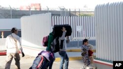 A family leaves to apply for asylum in the United States, at the border, Jan. 25, 2019, in Tijuana, Mexico. 