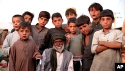 Working children gather around a paralyzed man on the outskirts of Kabul, Afghanistan, Sept. 23, 2019.