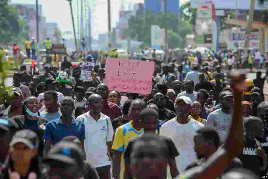 Manifestantes carregam cartazes durante manifestações contra o aumento de impostos, enquanto os deputados continuam a debater a Lei das Finanças de 2024, em Kisumu, no oeste do Quénia, a 20 de junho de 2024. (Fotografia de Brian ONGORO / AFP)