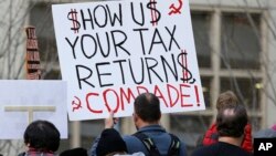 Tax FILE - A protester in Seattle holds a sign during a rally that reads "Show us your tax returns, Comrade" in reference to calls for President Donald Trump to release his tax returns and his alleged ties to Russia, April 15, 2017.