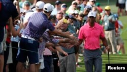 Tiger Woods of the U.S. slaps hands with patrons as he walks to the 8th tee during practice for the 2018 Masters golf tournament at Augusta National Golf Club in Augusta, Georgia, April 2, 2018.