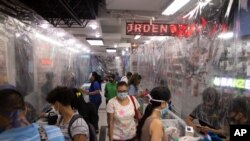 Compradores con mascarillas llenan una tienda de tecnología equipada con láminas de plástico usadas como cortinas protectoras, en Caracas. Junio 5 de 2020.