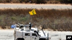 Spanish U.N. peacekeepers patrolling along the Lebanese-Israeli border pass a Hezbollah flag, in the southern Lebanese village of Kfar Kila, Lebanon, Sept. 2, 2019. 