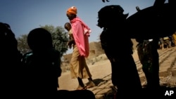 FILE - A Chadian women carries her child as others seek shade under a tree in Guelbanj, Chad, Feb. 10, 2008. Activists in Chad have launched a campaign to educate clerics and traditional rulers to help combat gender-based violence there.