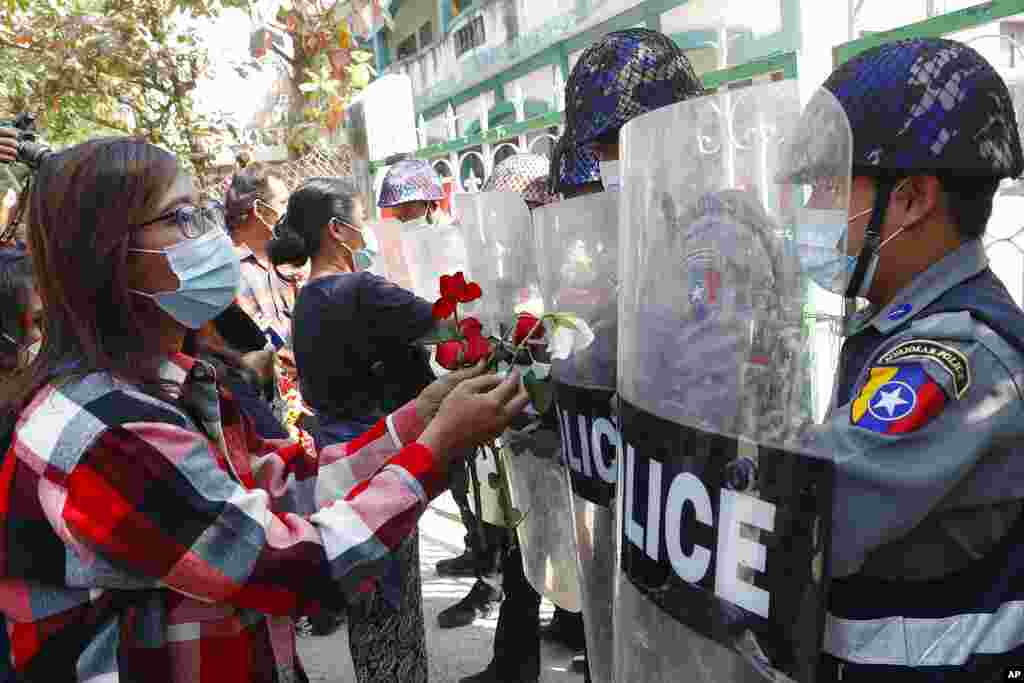 Supporters give roses to police while four arrested activists make a court appearance in Mandalay, Myanmar. Hundreds of students and teachers have taken to Myanmar&#39;s streets to demand the military hand power back to elected politicians.