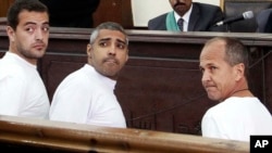 FILE - Al-Jazeera English producer Baher Mohamed, left, Canadian-Egyptian acting Cairo bureau chief Mohammed Fahmy, center, and correspondent Peter Greste, right, appear in court during their trial on terror charges, in Cairo, Egypt. 