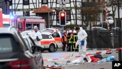 Police and rescue workers stand next to the scene of the accident with a car that is said to have crashed into a carnival parade in Volkmarsen, central Germany, Feb. 24, 2020.