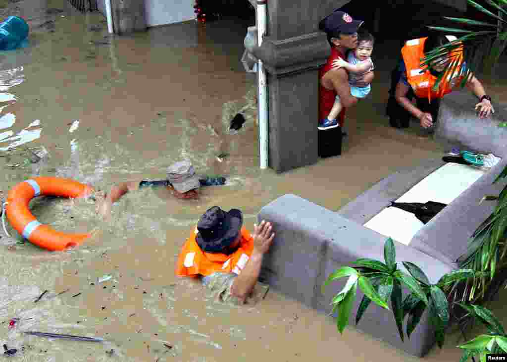 Policemen evacuate families trapped in their home during heavy flooding brought by tropical storm Seniang in Misamis Oriental, Mindanao island in southern Philippines, Dec. 29, 2014. Three people were killed, while more than 10,000 residents were evacuated due to heavy flooding, local media reported.