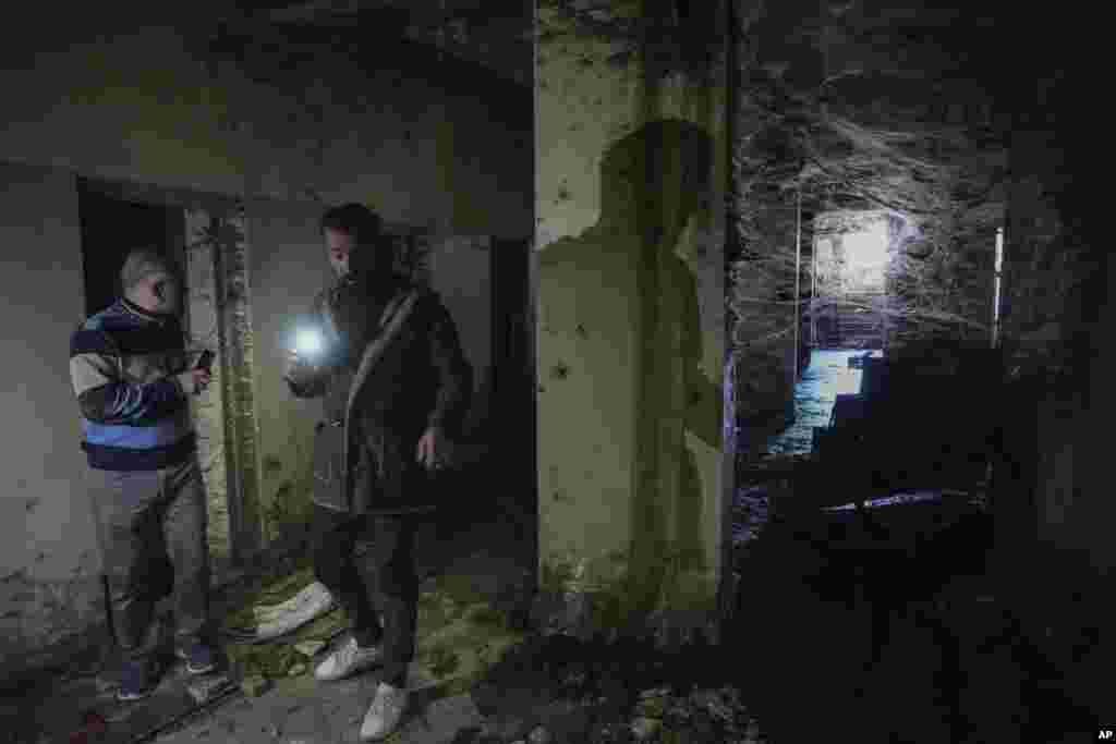 Two men use their flashlights to inspect a corridor of the infamous Saydnaya military prison, just north of Damascus, Syria, Dec. 9, 2024. 