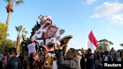 Supporters of the Libyan National Army hold a picture of Turkish President Recep Tayyip Erdogan as they celebrate near a Turkish military armored vehicle, which the LNA said it confiscated during Tripoli clashes, in Benghazi, Jan. 28, 2020. 