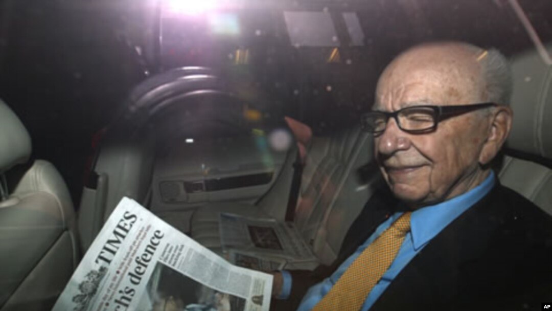 News Corp Chief Executive and Chairman Rupert Murdoch holds a copy of The Times newspaper as he leaves his home in London July 20, 2011